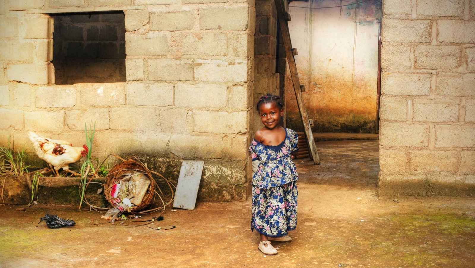 A girl stands in a courtyard beside her home